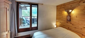 A bedroom with a wooden headboard, a bed, a window with curtains, and a view of the outdoors.
