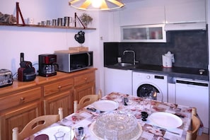 A compact kitchen with a microwave, toaster, coffee maker, and a washing machine.