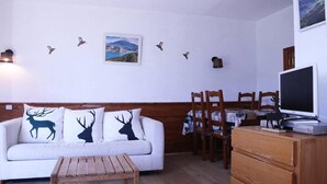 A cozy living room with a white sofa, wooden coffee table, and a TV on a wooden cabinet. - Ski-in/ski-out & foot of the slopes, 3rd floor, balcony, tv, ski locker, 30m², Les Orres (Les Orres)