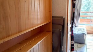 Een kamer met houten lambrisering, een bed, een koffer en een raam met gordijnen.