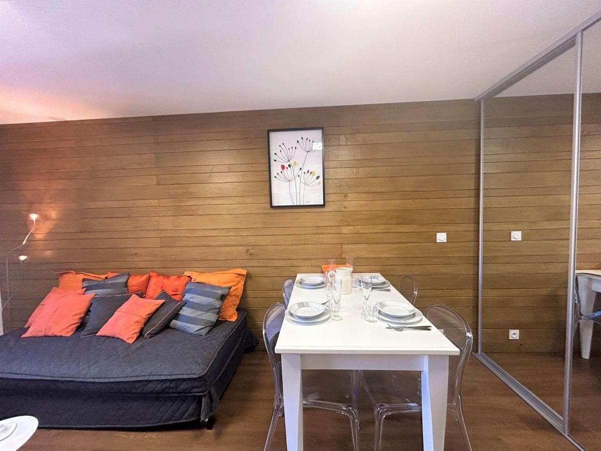 Una habitación moderna con una cama, una mesa de comedor para dos personas y una pared de madera.