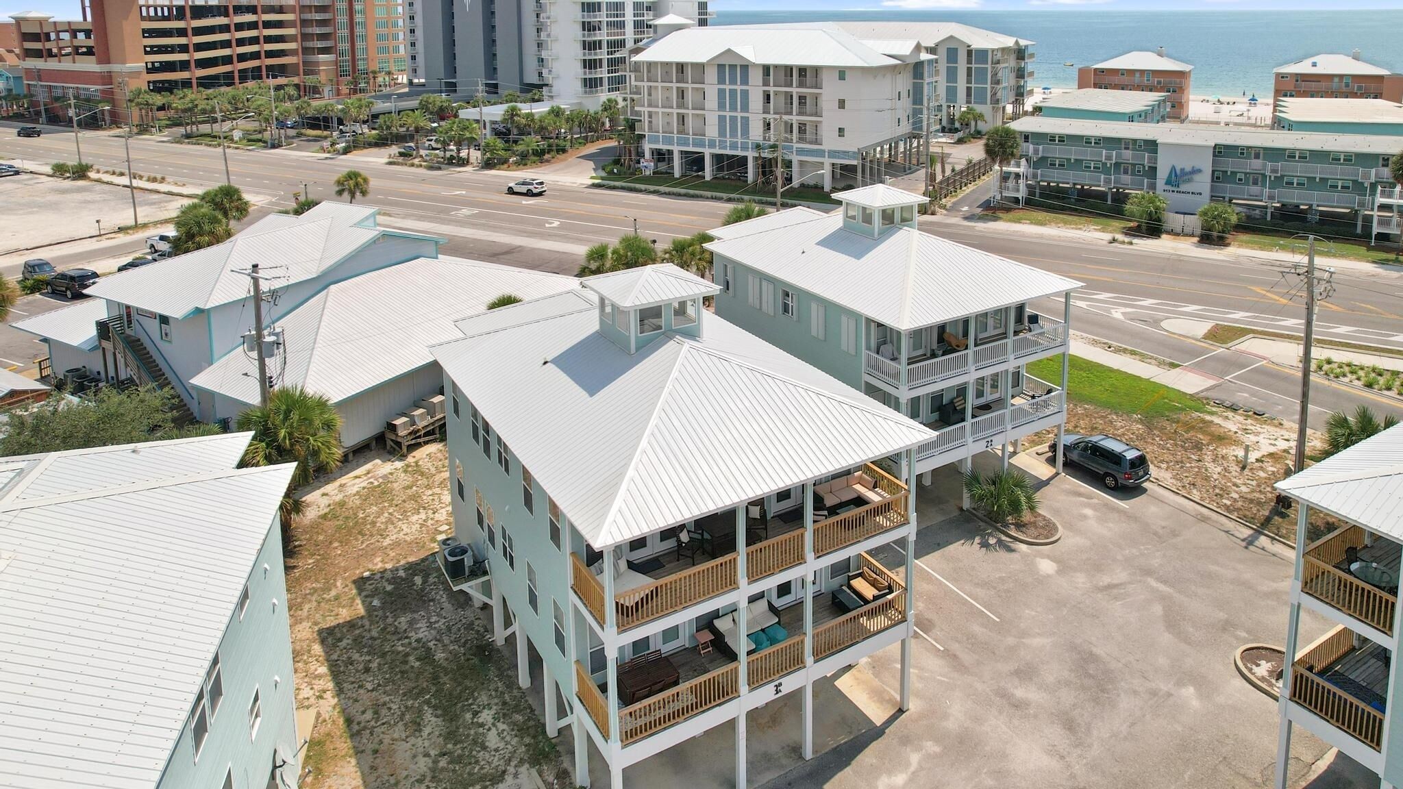 A beachfront hotel with multiple-story buildings, balconies, and a parking area.