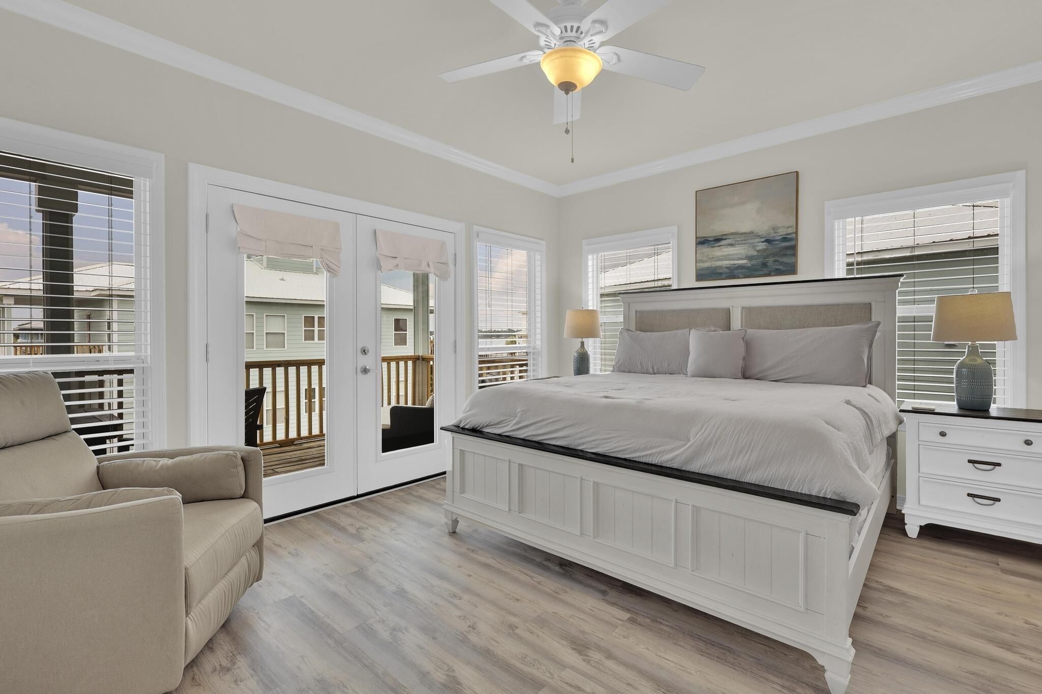 A bedroom with a large bed, a ceiling fan, and a view through the door.