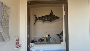 A reception area with a mounted fish decoration, a signboard for Sea Breeze Motel, and a small table with a vase of flowers. - Sea Breeze Motel (Pacifica)