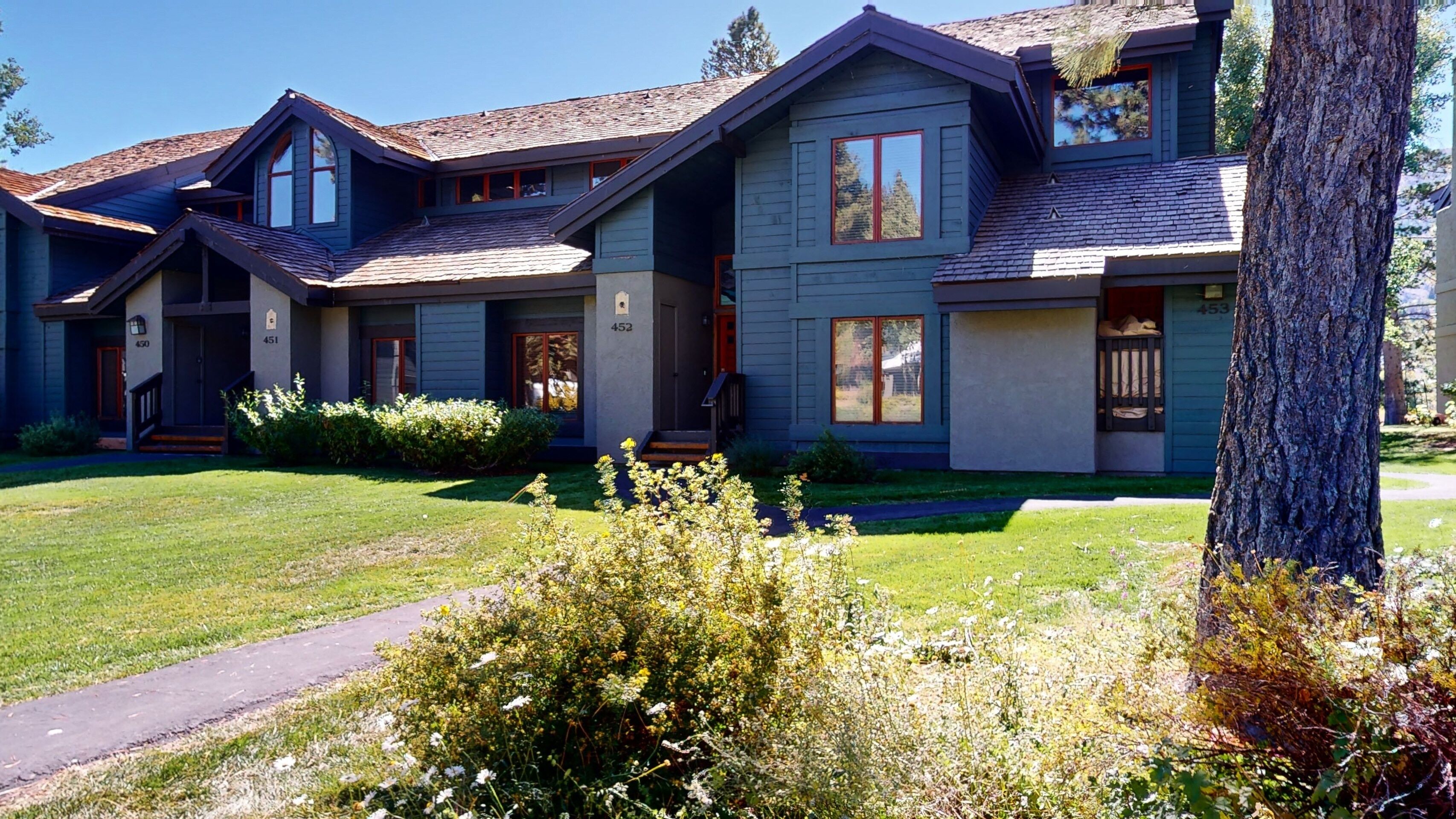 A modern two-story house with a well-maintained lawn and a pathway leading to the entrance.