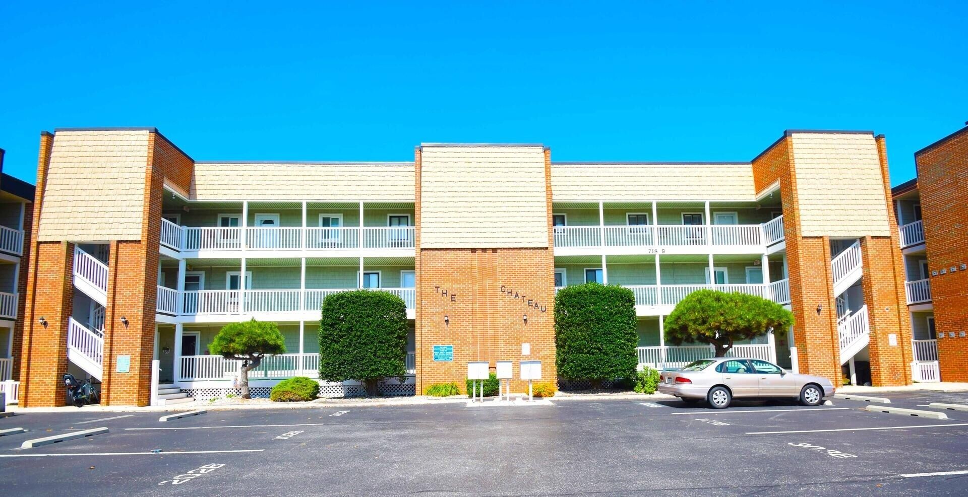 Un hôtel à plusieurs étages, doté d’une façade en briques, de balcons et d’un parking.