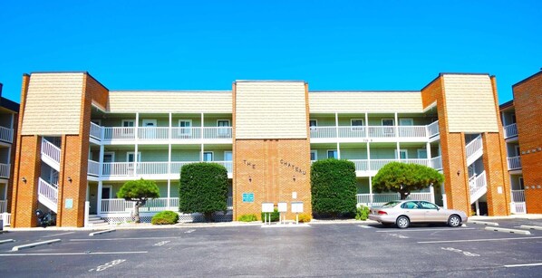 Ein mehrstöckiges Hotel mit Backsteinfassade, Balkonen und einem Parkplatz.