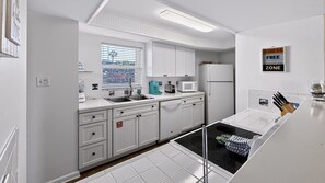 A modern kitchen with white cabinetry, a built-in dishwasher, and a microwave. - 114 El Matador 1 Bedroom Condo by RedAwning (Fort Walton Beach)
