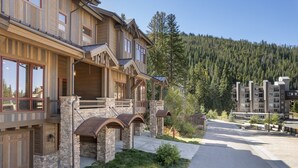 A multi-story building with a stone facade, large windows, and a balcony. - Base Camp At Iron Horse... 4 Bedroom Townhouse by RedAwning (Winter Park)