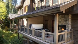 A wooden deck with a stone fireplace, surrounded by a stone wall and a wooden railing. - Base Camp At Iron Horse... 4 Bedroom Townhouse by RedAwning (Winter Park)