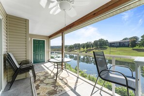 A balcony with a view of a lake, a table, chairs, and a door. - Harmony Hideaway 2 Bedroom Condo by RedAwning (Branson)