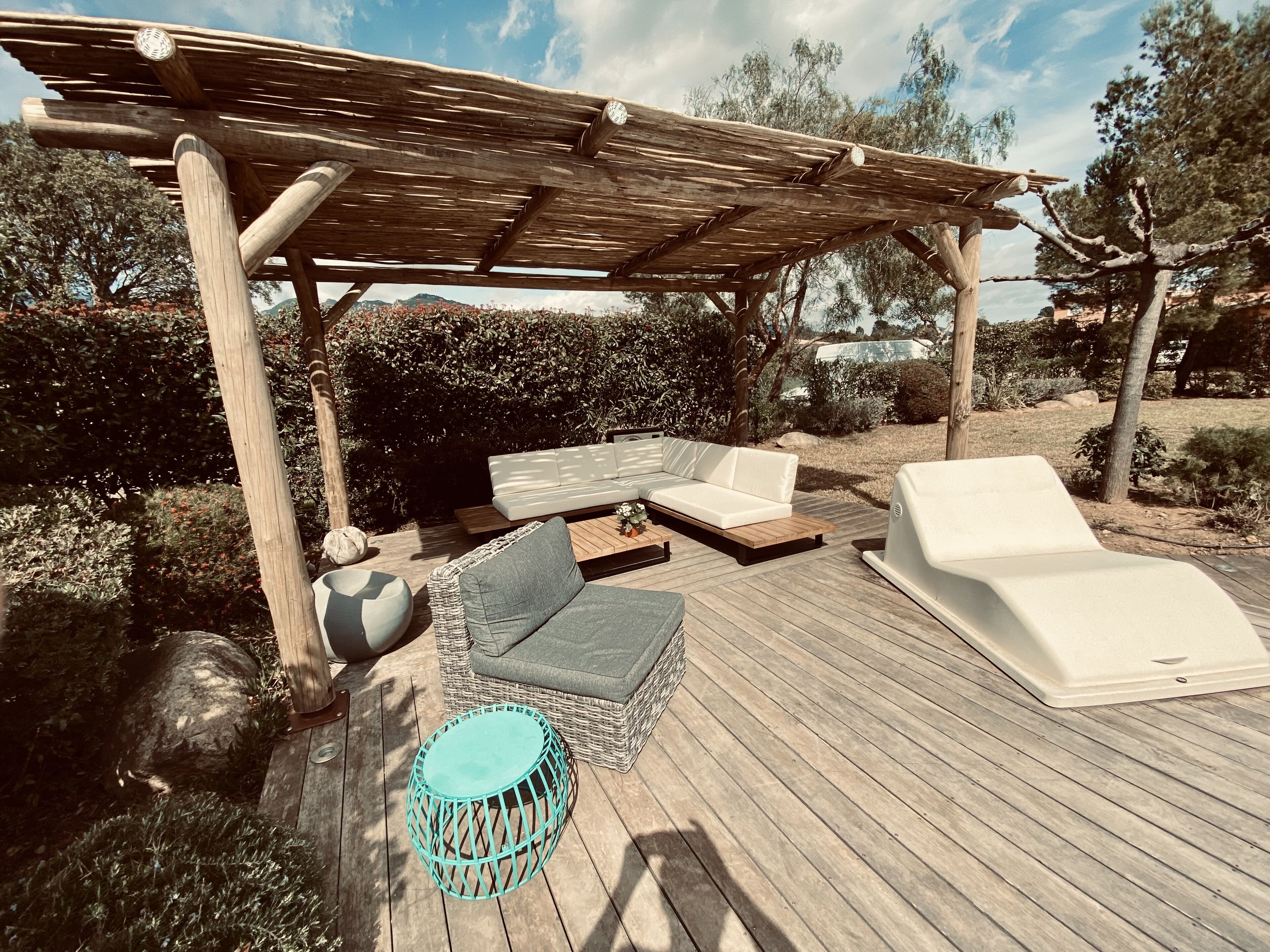 Una terraza de madera con mobiliario exterior, incluyendo un sofá, sillas y una mesa redonda.