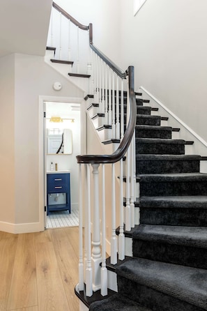 Bright entryway with a stylish staircase and convenient half bath.