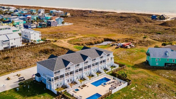 Un grand immeuble à plusieurs étages, doté d’une piscine et offrant une vue sur la plage.