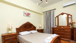 Une chambre à coucher bien rangée, avec un lit en bois, une table de chevet avec une lampe, une commode avec un miroir et un tableau accroché au mur.