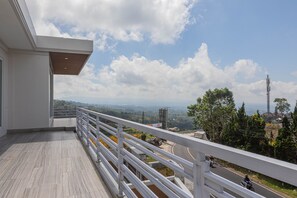 A balcony with a view of a road and distant landscape.