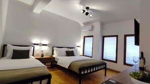 Habitación de hotel con dos camas, lámparas de noche, una mesita de noche, una planta en maceta y una ventana con persianas.