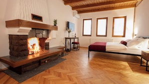 Un dormitorio con chimenea de piedra, suelo de madera y cama con manta roja.