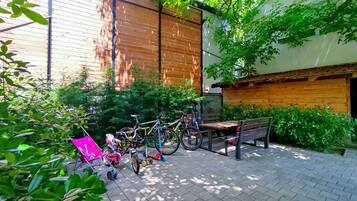 Un patio empedrado con bicicletas, un cochecito de bebé y una banca.