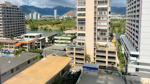 Un immeuble de grande hauteur doté de nombreux balcons, offrant une vue sur la ville et les montagnes en arrière-plan.