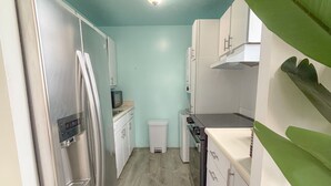 Une cuisine étroite aux murs bleu clair, dotée d’appareils électroménagers en acier inoxydable et d’un plancher en bois.