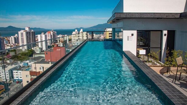 A rooftop pool with a city view, surrounded by buildings and a clear sky.