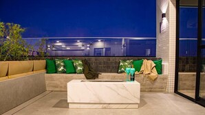 A modern outdoor seating area with a marble bench and green cushions.