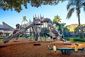 A playground with slides and swings, surrounded by trees and a sign for The Westin St. John Resort & Villas.