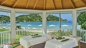 Un belvédère abritant deux tables de massage, une terrasse en bois et offrant une vue sur la mer et les collines.