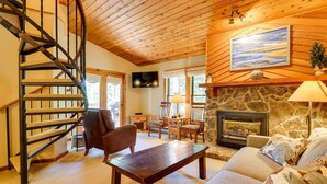 A cozy living room with a wooden staircase, a fireplace, a comfortable sofa, and a dining area. - Winter Park Condo w/ Sleeping Loft - Near Main St (Winter Park)