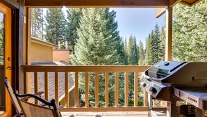 A balcony with a grill, chairs, and a view of tall trees. - Winter Park Condo w/ Sleeping Loft - Near Main St (Winter Park)