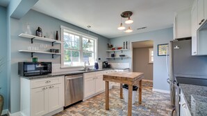 A modern kitchen with white cabinets, a wooden table, and a built-in microwave. - '1001 Sevier Bungalow': 2 Mi to Neyland Stadium! (Knoxville)
