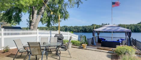 An outdoor patio with a table and chairs, a covered seating area, and a view of a lake.