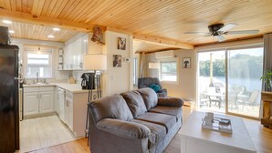 Een moderne keuken met witte kasten, een zwarte koelkast en een plafondventilator.