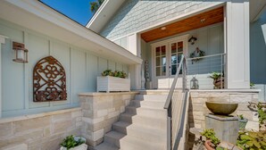 A house with a stone staircase leading to a wooden porch, a decorative metal piece on the wall, and potted plants. - Beautiful Marble Falls Getaway on Lake Lbj! (Marble Falls)