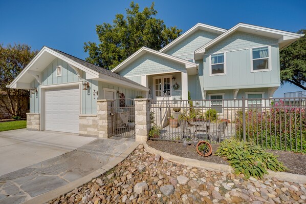 A two-story house with a garage, a front porch, and a fenced yard with potted plants. - Beautiful Marble Falls Getaway on Lake Lbj! (Marble Falls)