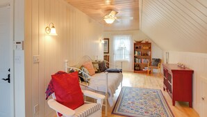 Une chambre mansardée chaleureuse, avec un lit, une chaise, une bibliothèque et un petit bureau.