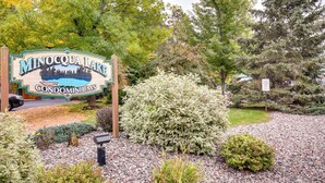 Un letrero de Minocqua Lake Condominiums rodeado de jardines y árboles.