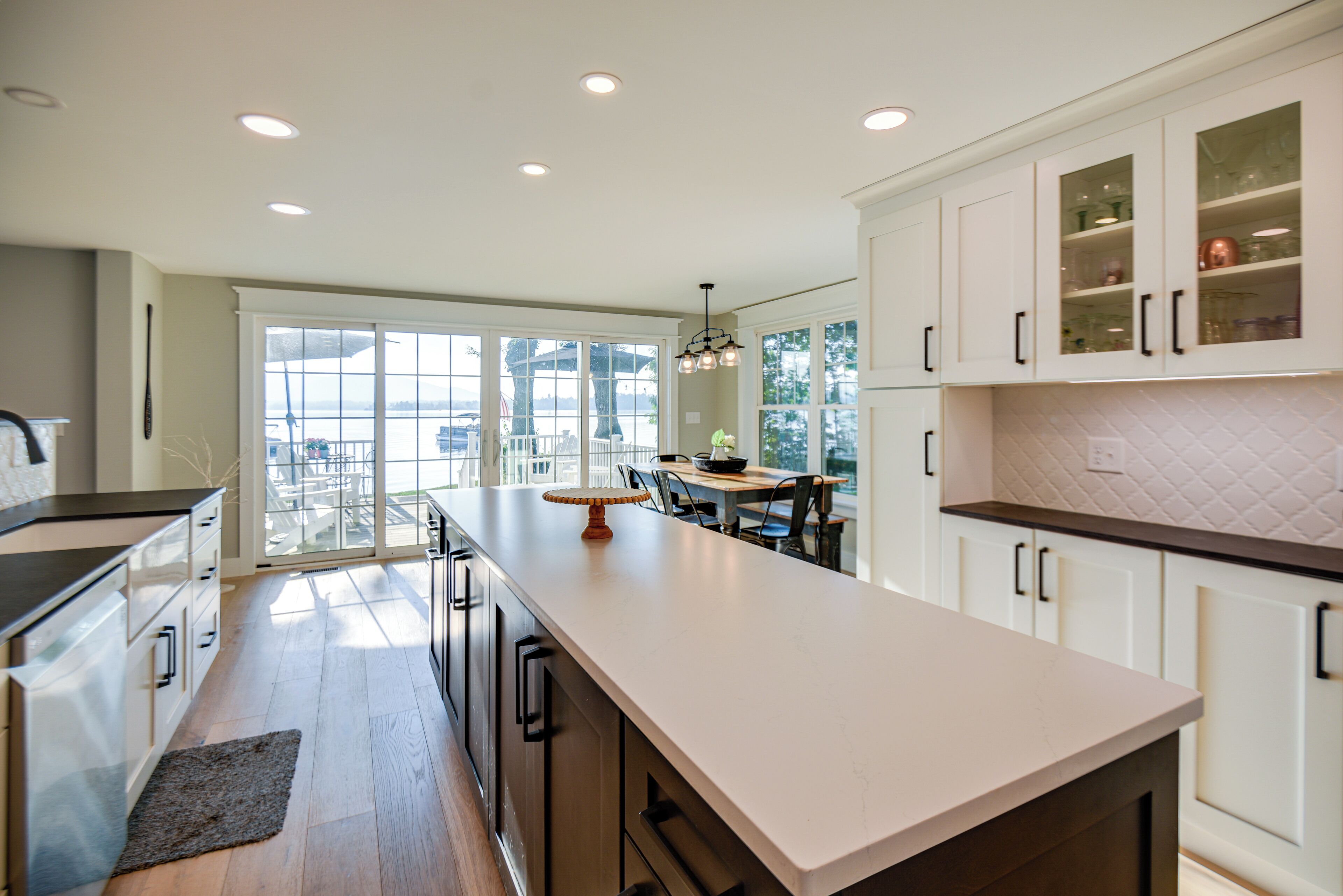 A modern kitchen with white cabinets, a large island, and a view to the outside.