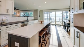 A modern kitchen with a large island, bar stools, and a view to the outside. - Lakefront Center Ossipee Home w/ Boat Dock! (Center Ossipee)