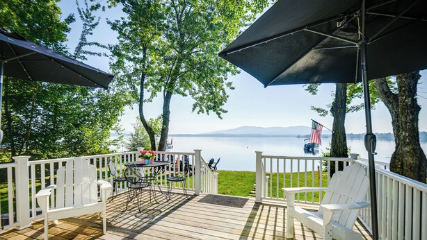 A wooden deck with white railings, outdoor furniture, and a view of a lake. - Lakefront Center Ossipee Home w/ Boat Dock! (Center Ossipee)