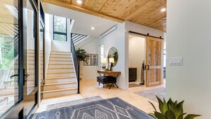 A modern interior with a staircase, wooden flooring, and a large mirror. - Modern Turnerville Cabin w/ Hot Tub & Scenic Views (Bedford)