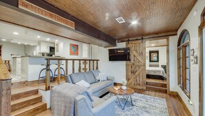 A cozy living area with a sofa, coffee table, and a staircase leading to a loft bedroom. - Mississippi Retreat w/ Hot Tub, Deck & Lake Views! (Terry)