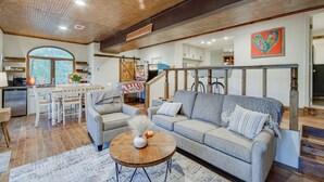 A spacious living area with a wooden ceiling, a large sofa, a coffee table, and a dining area with a kitchen in the background. - Mississippi Retreat w/ Hot Tub, Deck & Lake Views! (Terry)