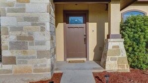 A stone-clad building with a brown door, a welcome mat, and a small pathway leading to the entrance.