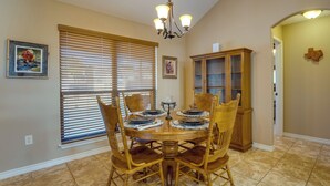 A dining area with a round table, wooden chairs, and a chandelier.