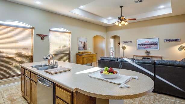 A kitchen with a central island, a dining area with a sofa, and a living room with a TV.