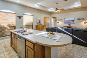 A kitchen with a central island, a dining area with a sofa, and a living room with a TV. - Pleasanton Vacation Rental w/ Private Yard! (Pleasanton)