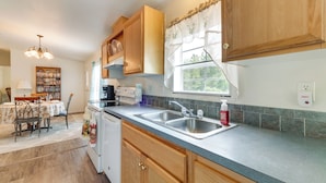 A kitchen with wooden cabinets, a double sink, and a window with curtains. - Weeki Wachee Home w/ Fire Pit: 13 Mi to Ocean! (Brooksville)