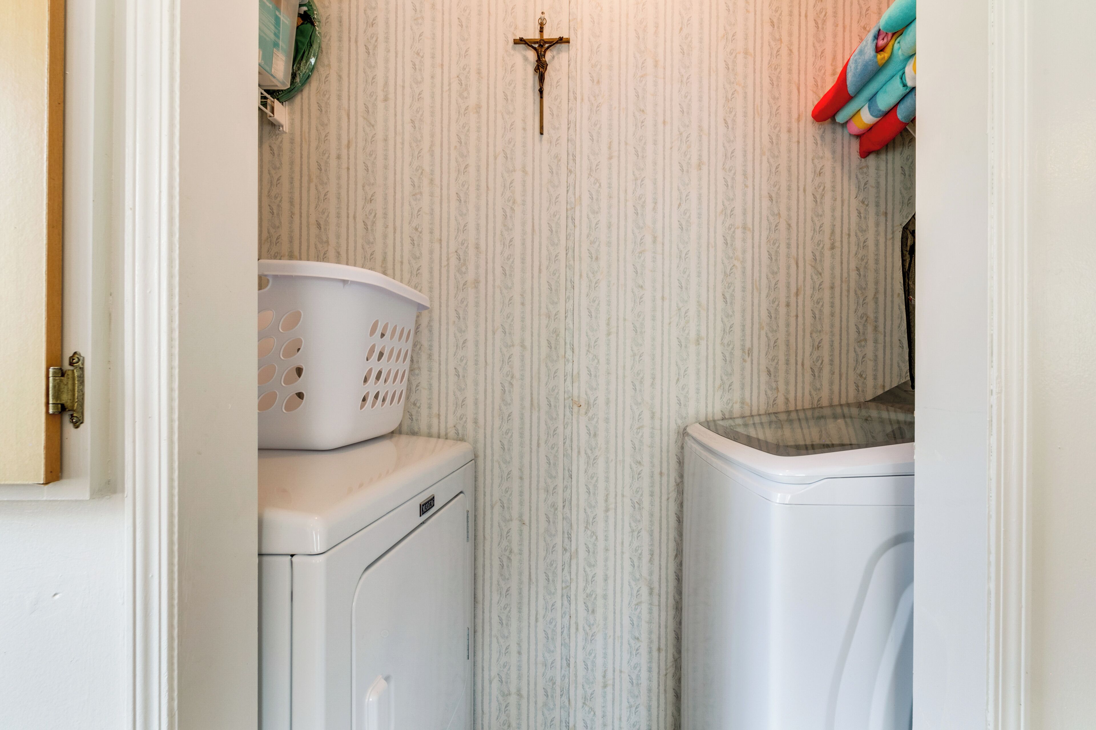 A laundry room with a washing machine, dryer, and a basket on the dryer.